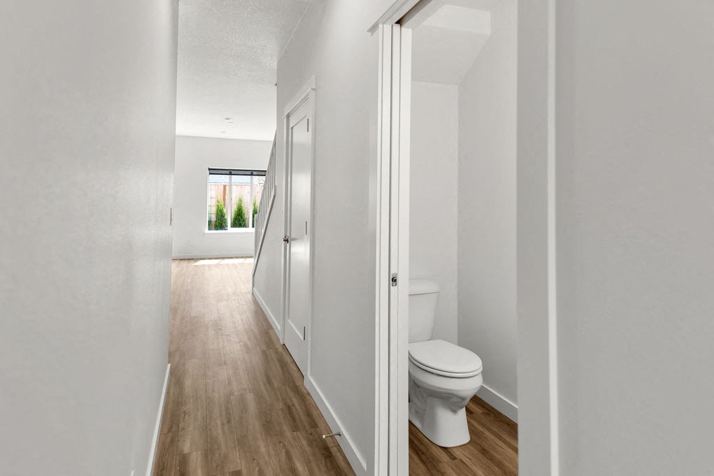 a bathroom with a toilet and a hallway with a door