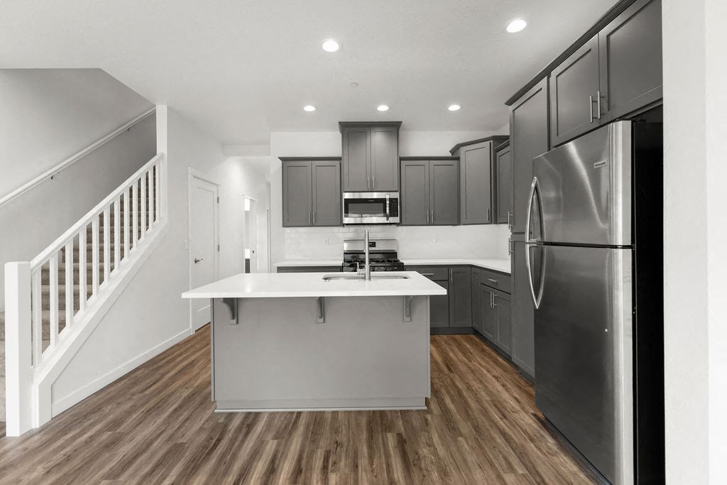 a kitchen with a white counter top and a stainless steel refrigerator