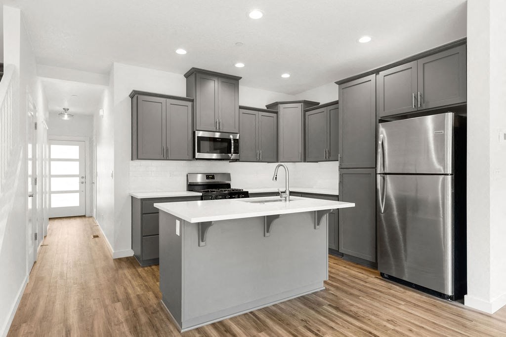 a kitchen with a large island and stainless steel refrigerator