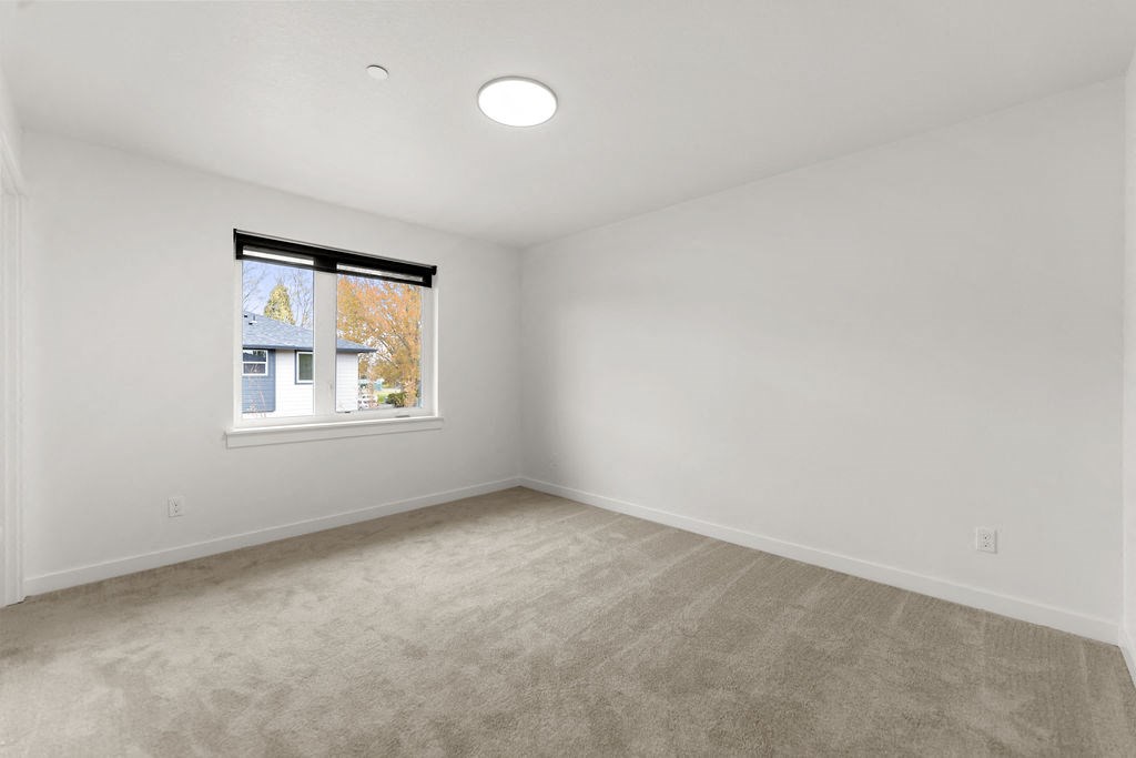 an empty living room with a window and carpet