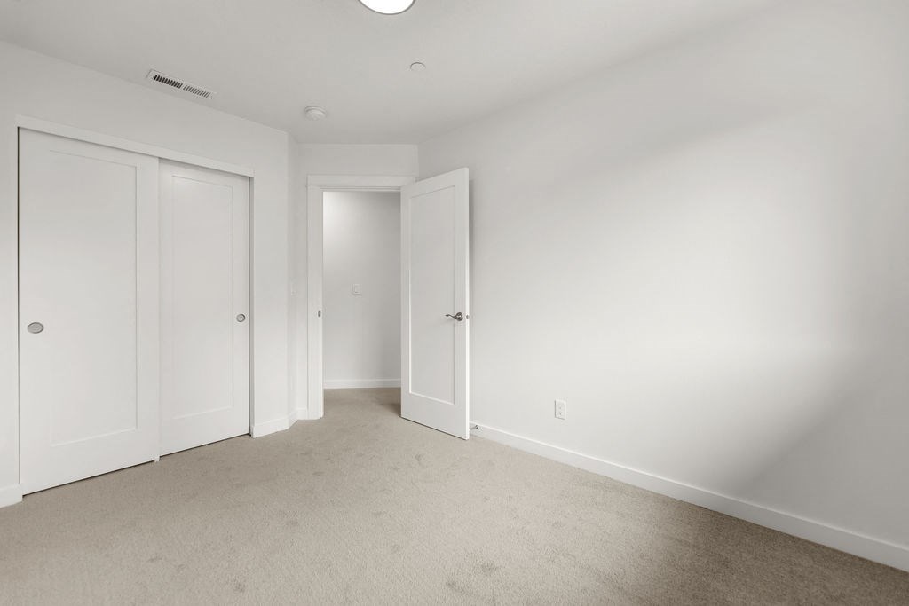 a bedroom with white walls and white doors and carpet