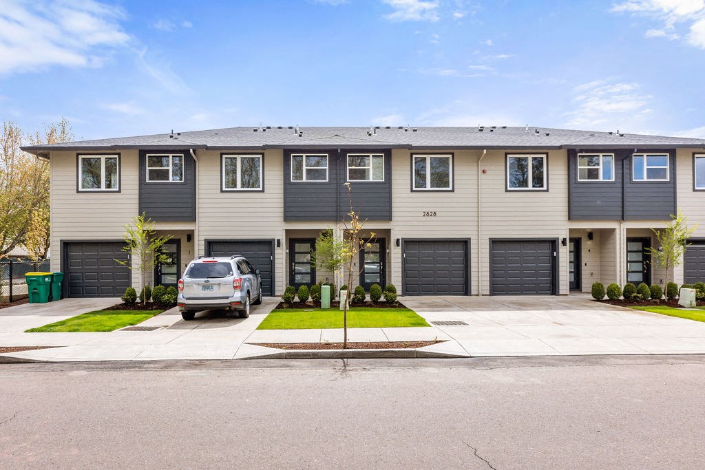 a large apartment building with a car parked in the driveway