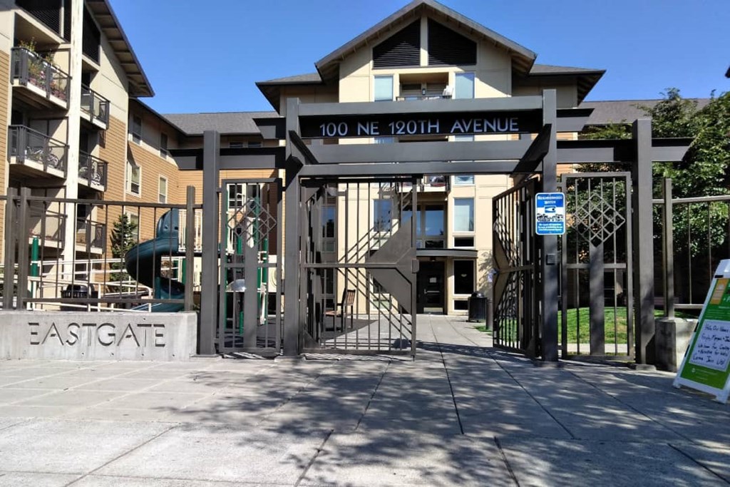 a gate is open in front of a building with a playground in the background