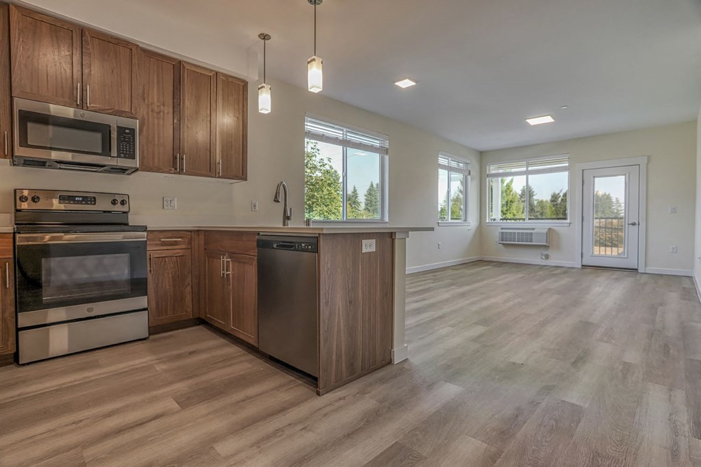 a kitchen and living room with wood floors and wooden cabinets