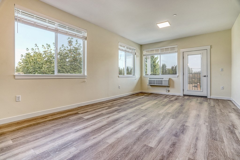 a bedroom with hardwood floors and a door leading to a balcony