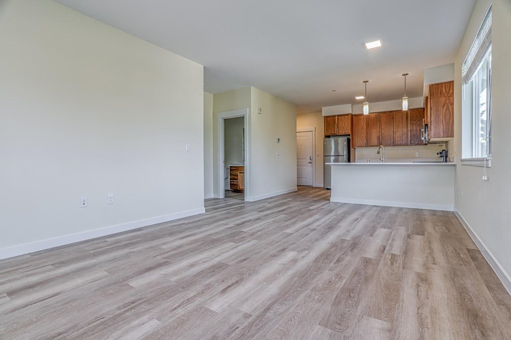 a spacious living room with a kitchen in the background