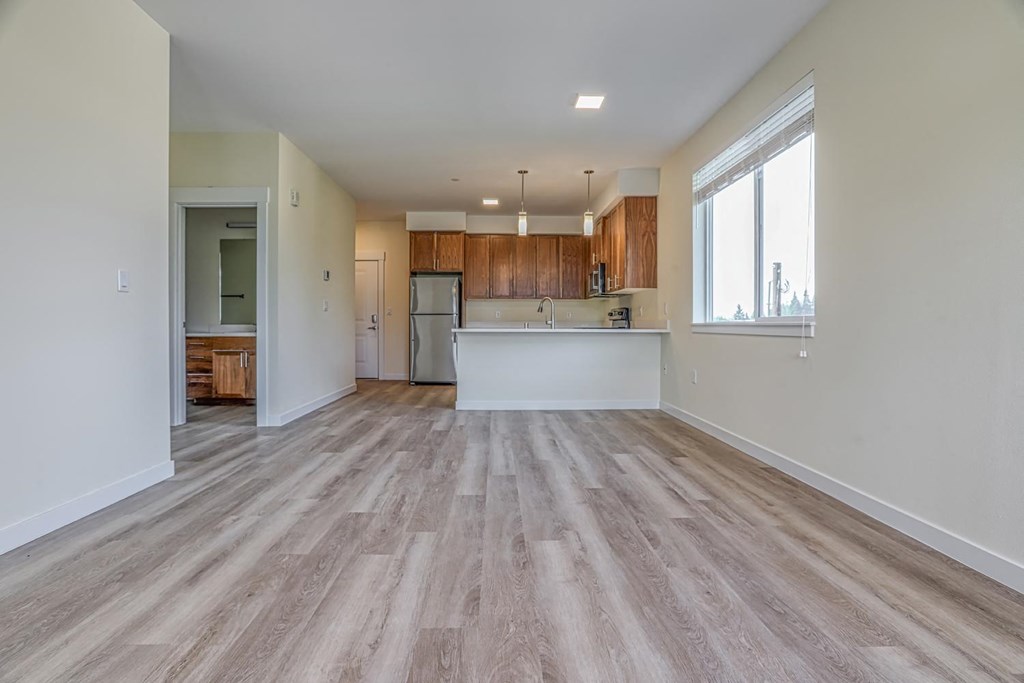 a spacious living room with a kitchen in the background