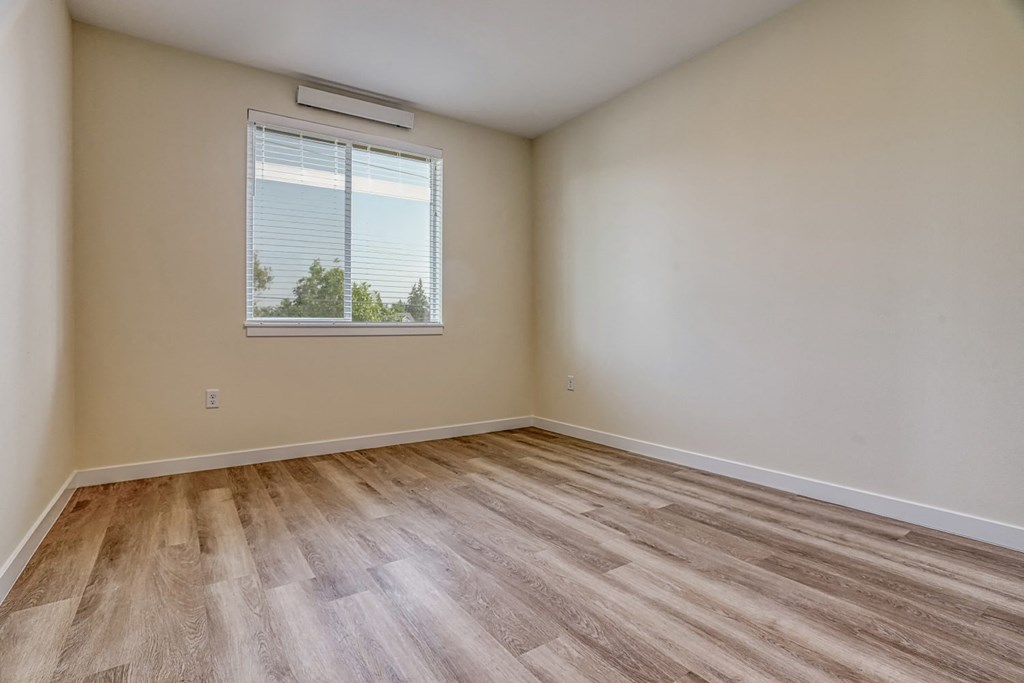 a bedroom with hardwood floors and a window