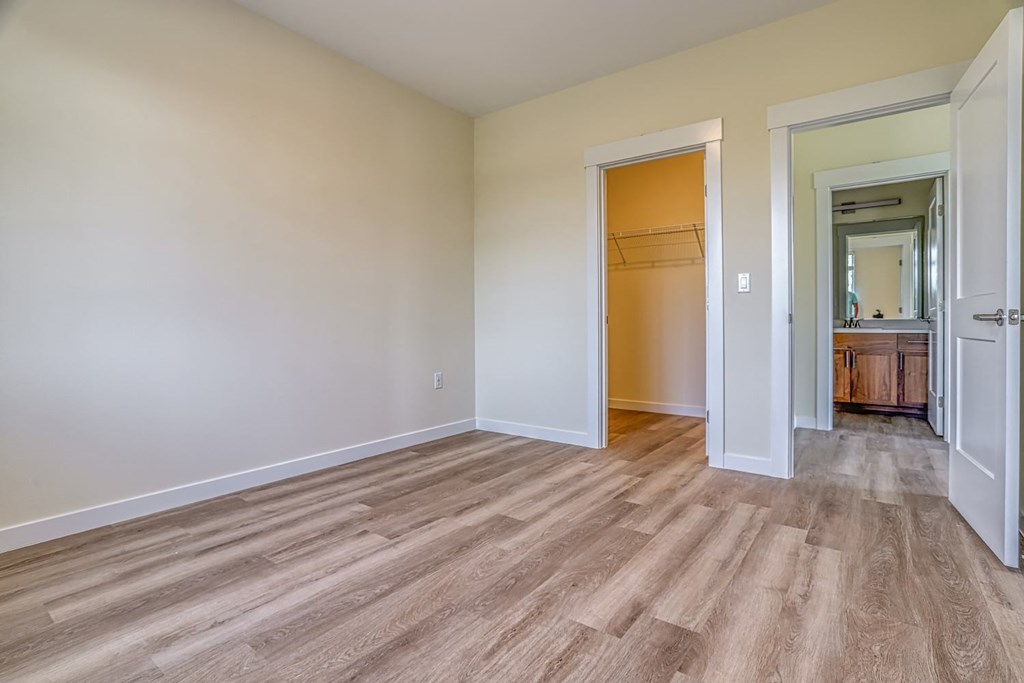 a bedroom with hardwood floors and white walls