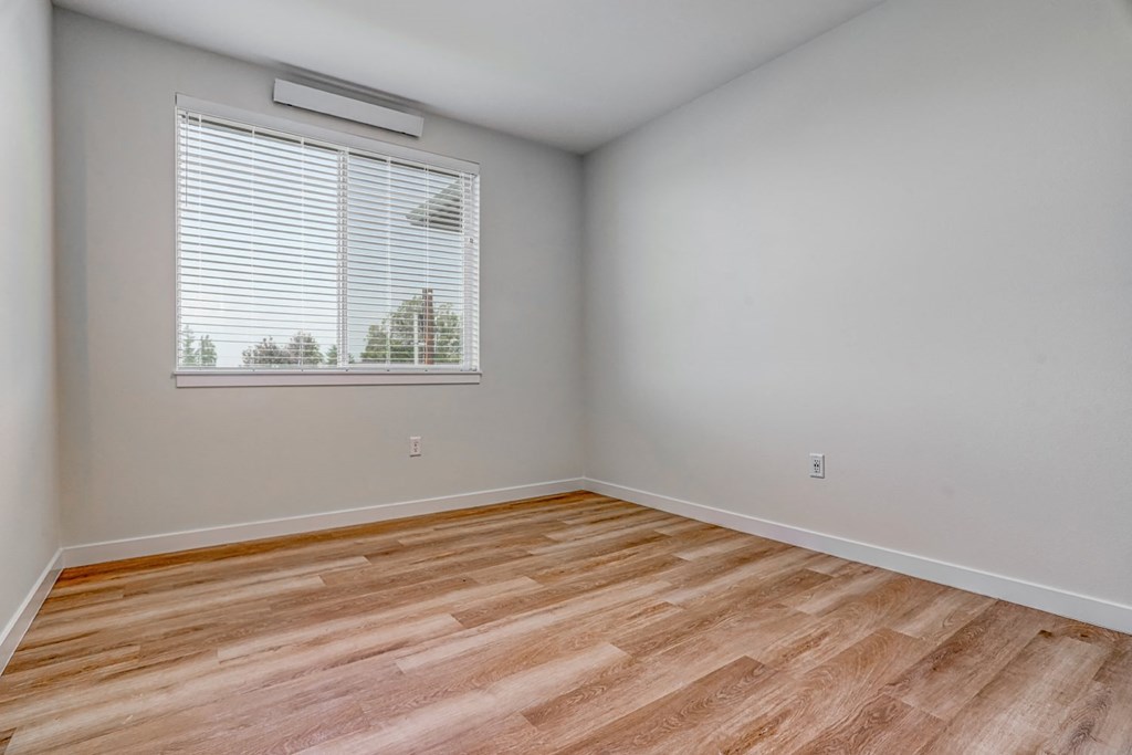 a bedroom with hardwood floors and a large window
