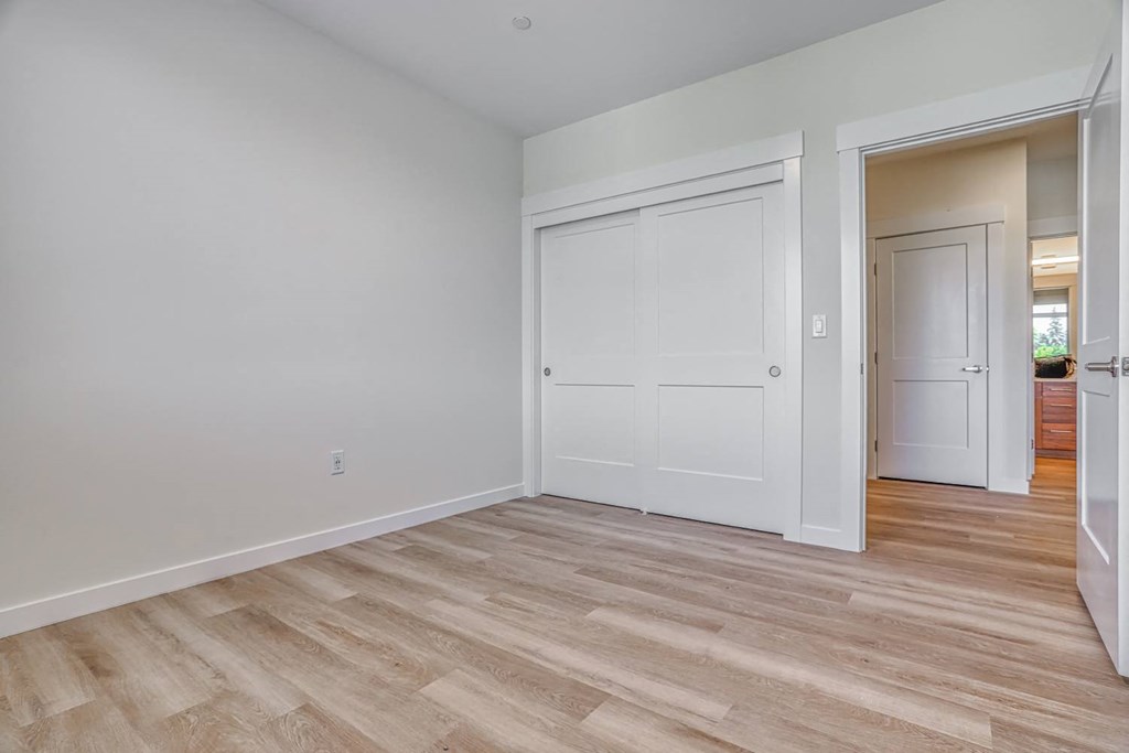 a bedroom with hardwood floors and white walls