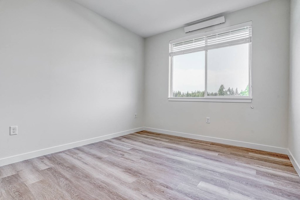 a bedroom with hardwood floors and a large window