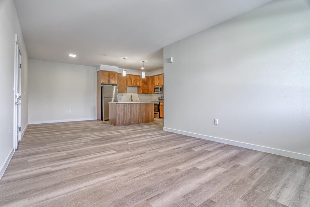a spacious living room with a kitchen in the background