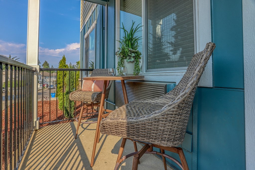 a patio with a wicker rocking chair and a table with a potted plant on a