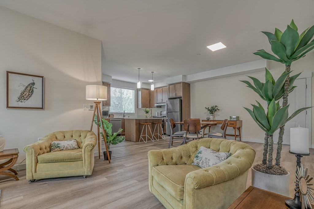 a living room with two couches and a table with chairs and a kitchen in the background