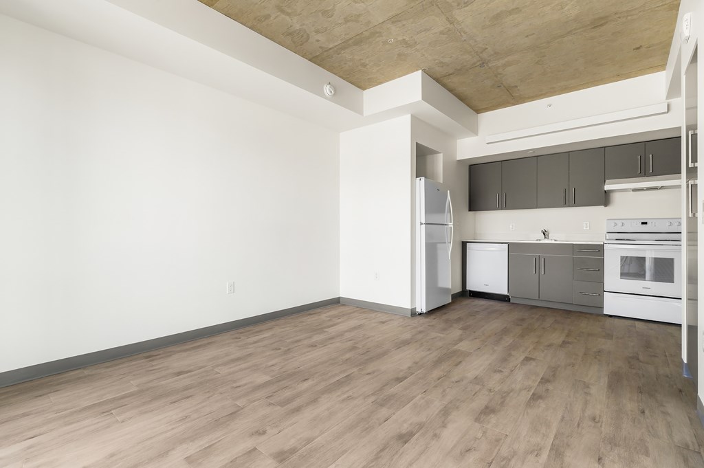 A kitchen with white appliances and wooden floors.