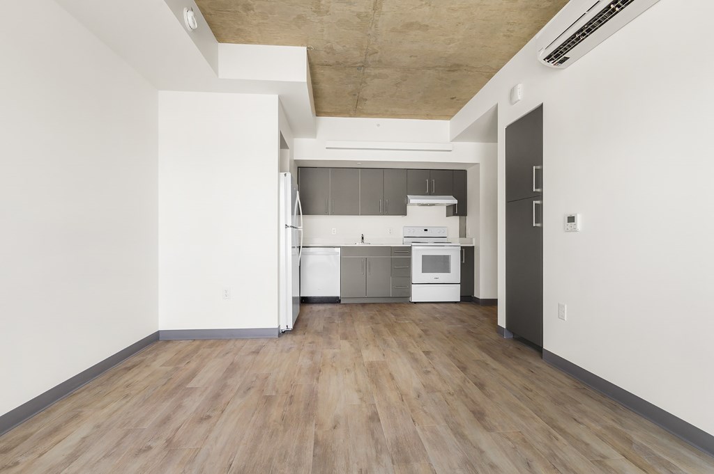 A kitchen with white appliances and wooden floors.