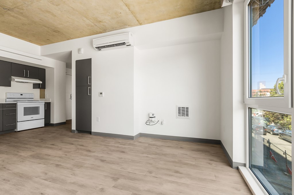 A kitchen with a white countertop and a window overlooking a parking lot.