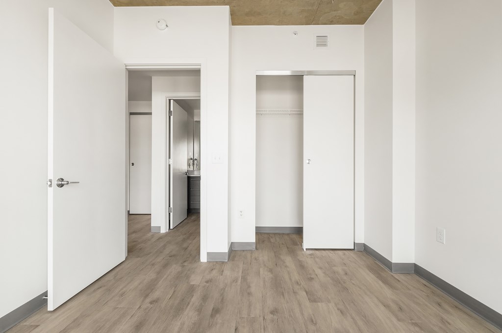 A white door is open to a hallway with wood floors.