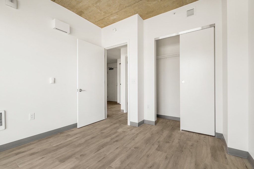 A room with white walls and wood flooring with two open doors.