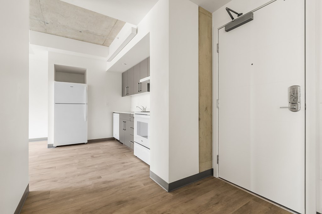 A kitchen with white appliances and wooden floors.