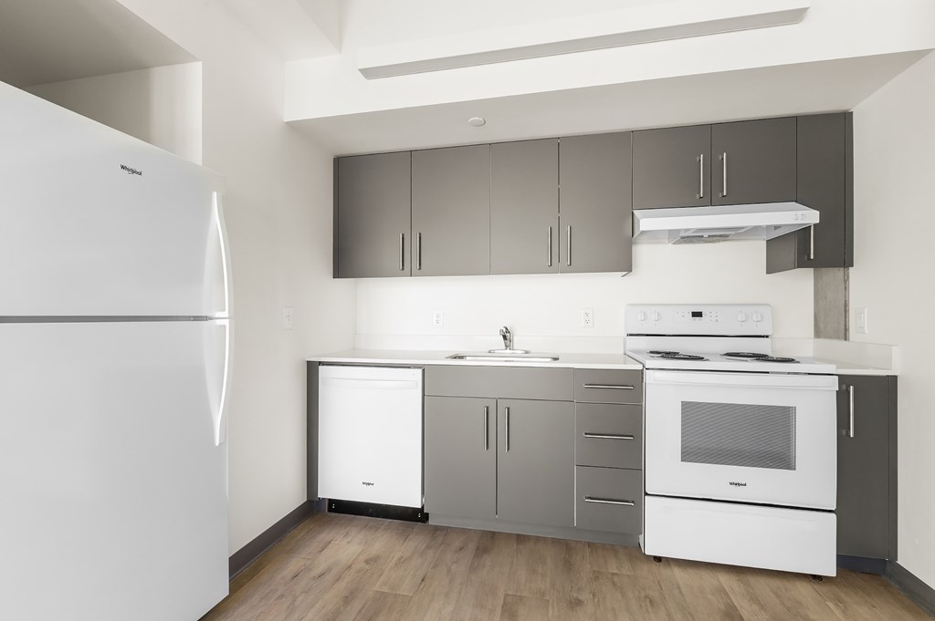 A white refrigerator stands in a kitchen with a white stove and oven.