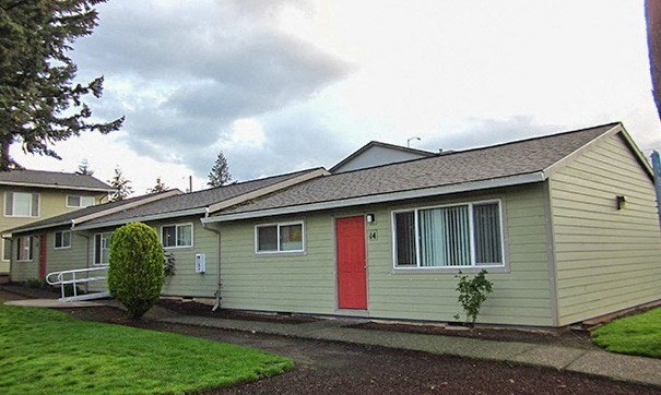 a yellow house with a red door and a yard