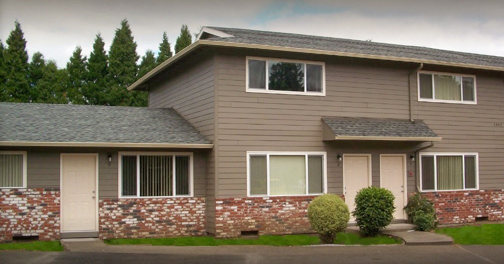 a brown house with a brick wall and a gray roof