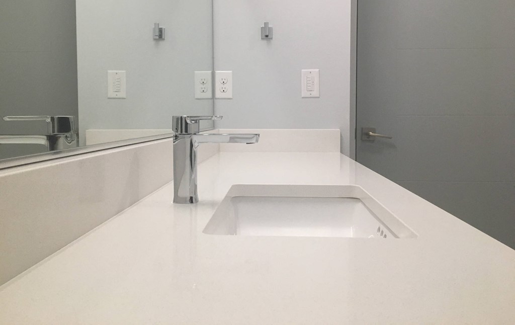 a white counter with a sink and a mirror in a bathroom