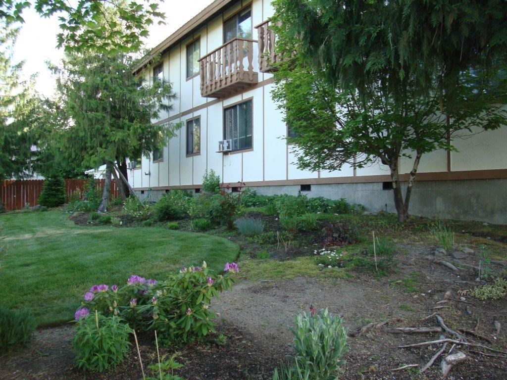 the side of a house with a garden in front of it