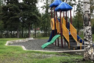 a playground with a yellow and blue slide and a green and yellow slide