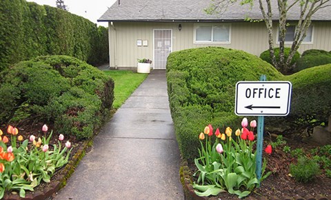 A white sign with the word office on it is in front of a building.