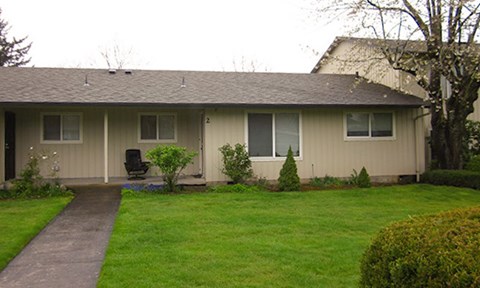 A house with a brown roof and a green lawn.