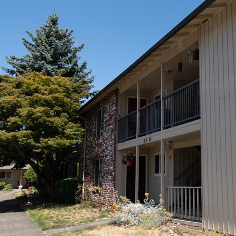 A building with a balcony and a tree in front of it.