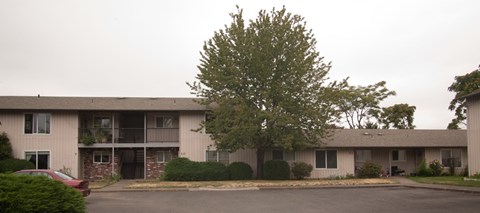 Apartment building with a red car parked in front.