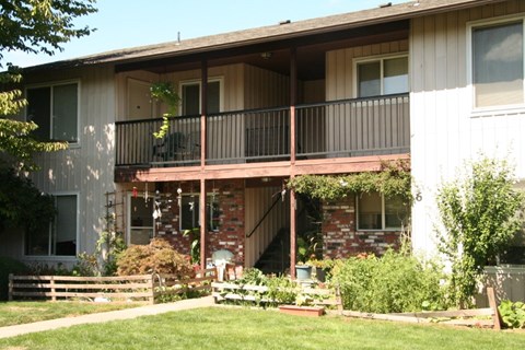 A house with a balcony and a garden in front.