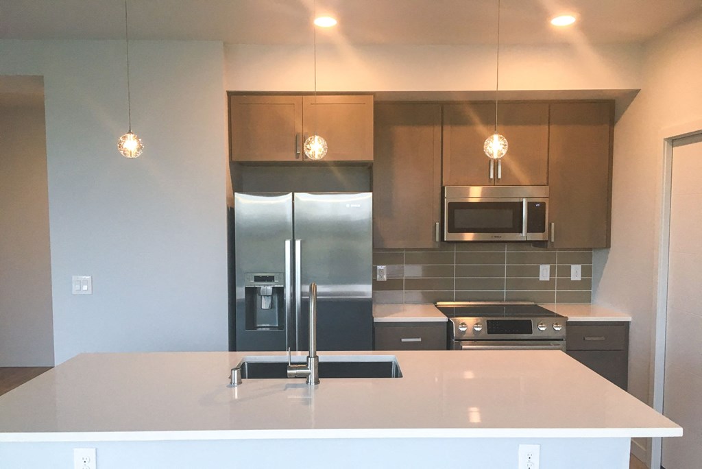 a kitchen with a white counter top and a stainless steel refrigerator