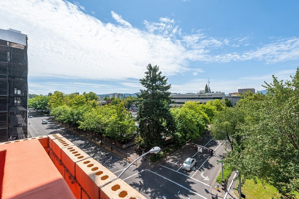 a view of a city street from a balcony with trees