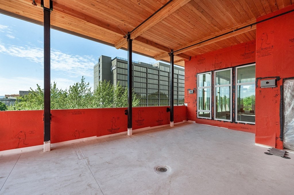 the upstairs patio of a building with red walls and glass windows
