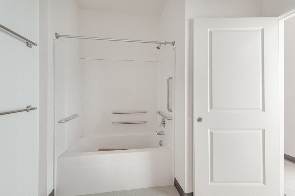 a white bathroom with a tub and shower and a white door