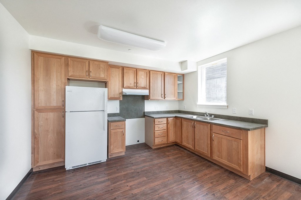 an empty kitchen with wooden cabinets and a white refrigerator