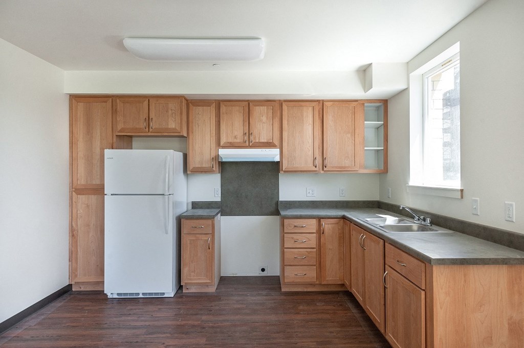 an empty kitchen with wooden cabinets and a white refrigerator