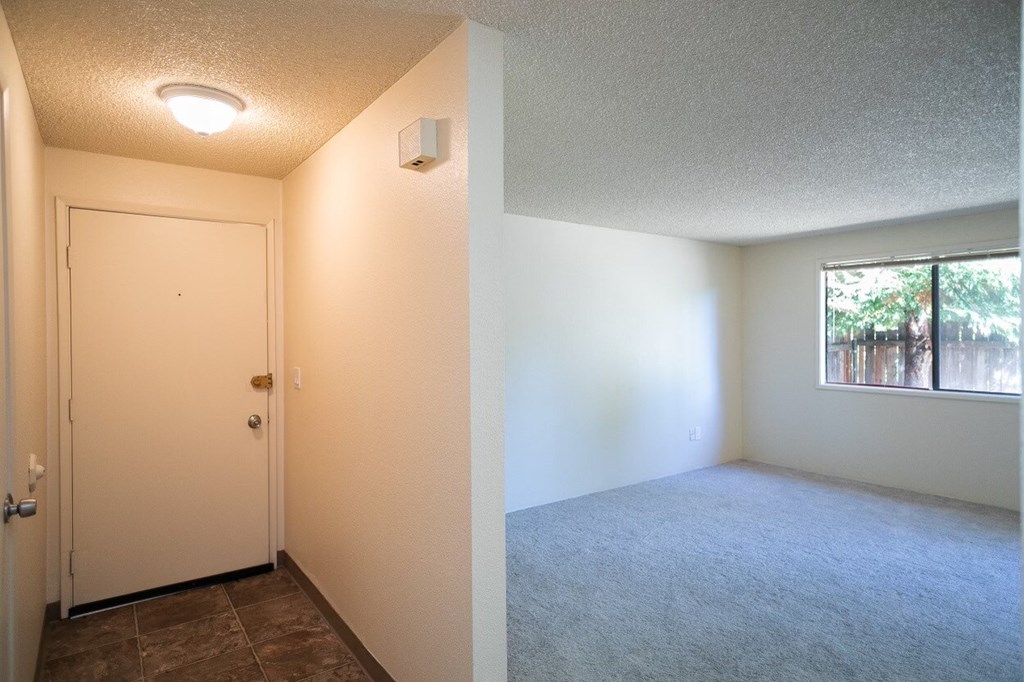an empty bedroom with a window and a door
