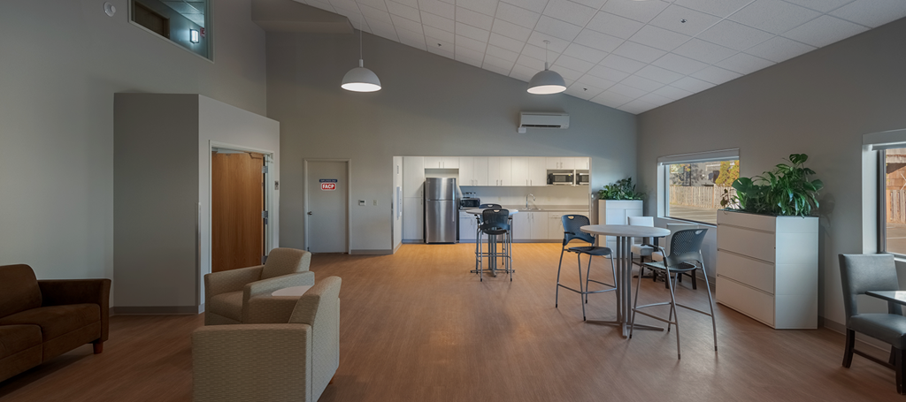 A room with a brown couch, chairs, and a dining table.