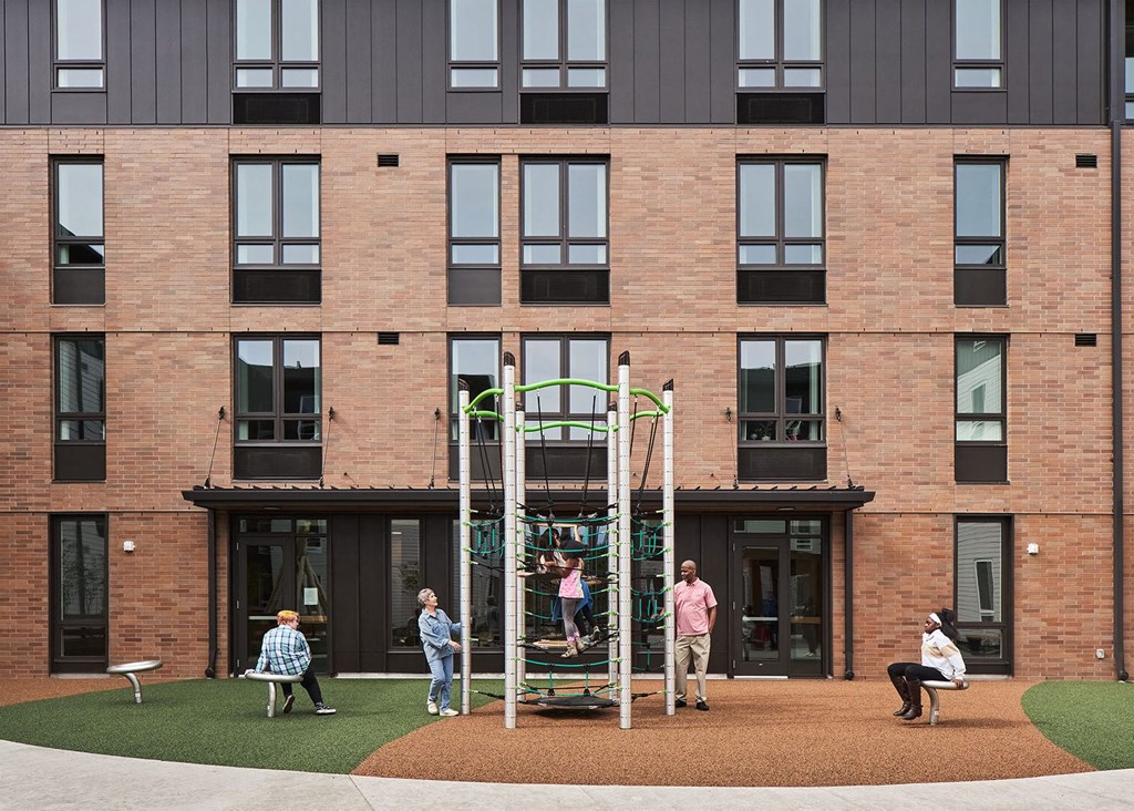 people playing on a playground in front of a brick building