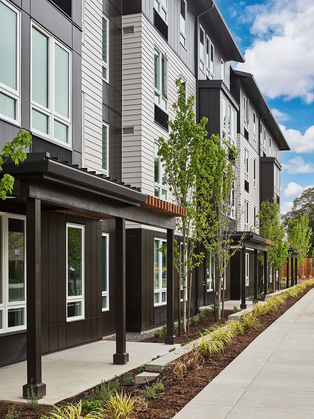 a sidewalk in front of a row of new apartment buildings