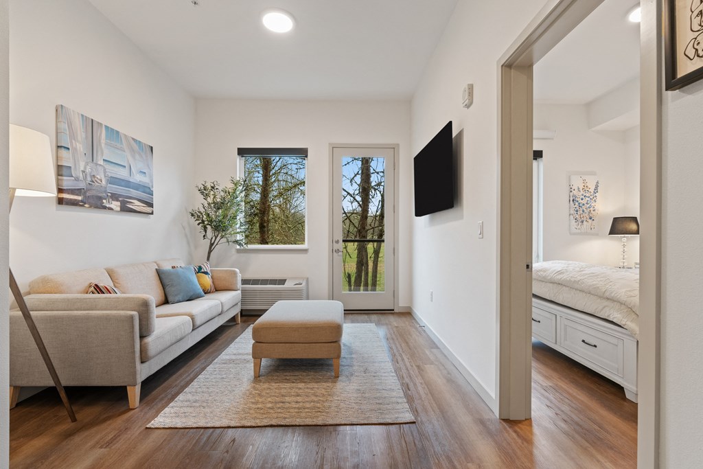 a living room with a couch and a chair and a door to a bedroom