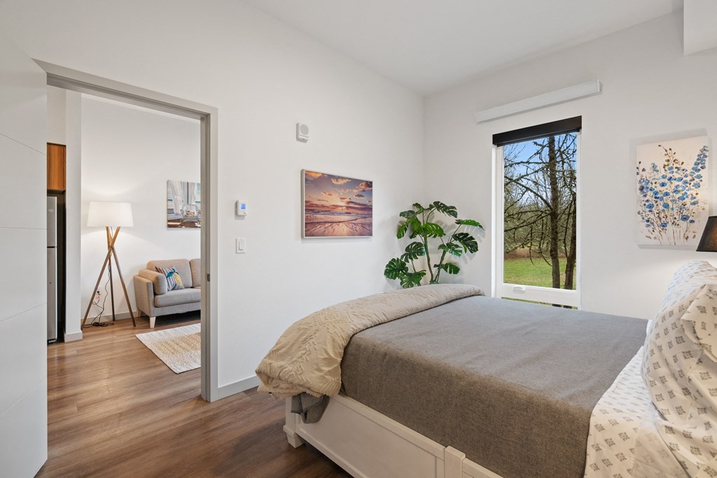 a bedroom with a bed and a door to a living room