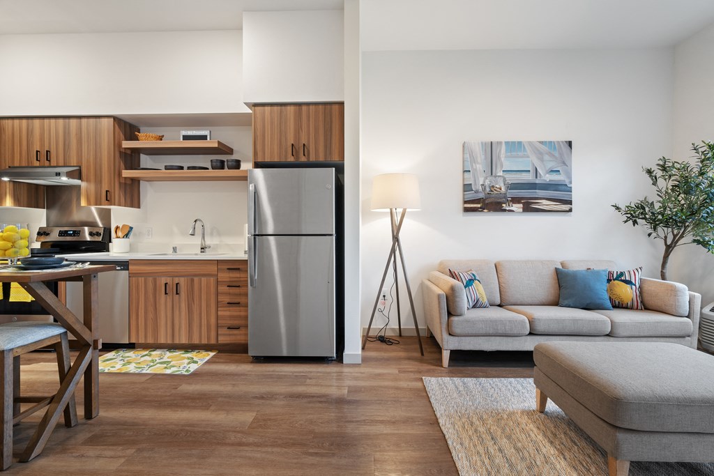 a living room with a couch and a kitchen with a refrigerator