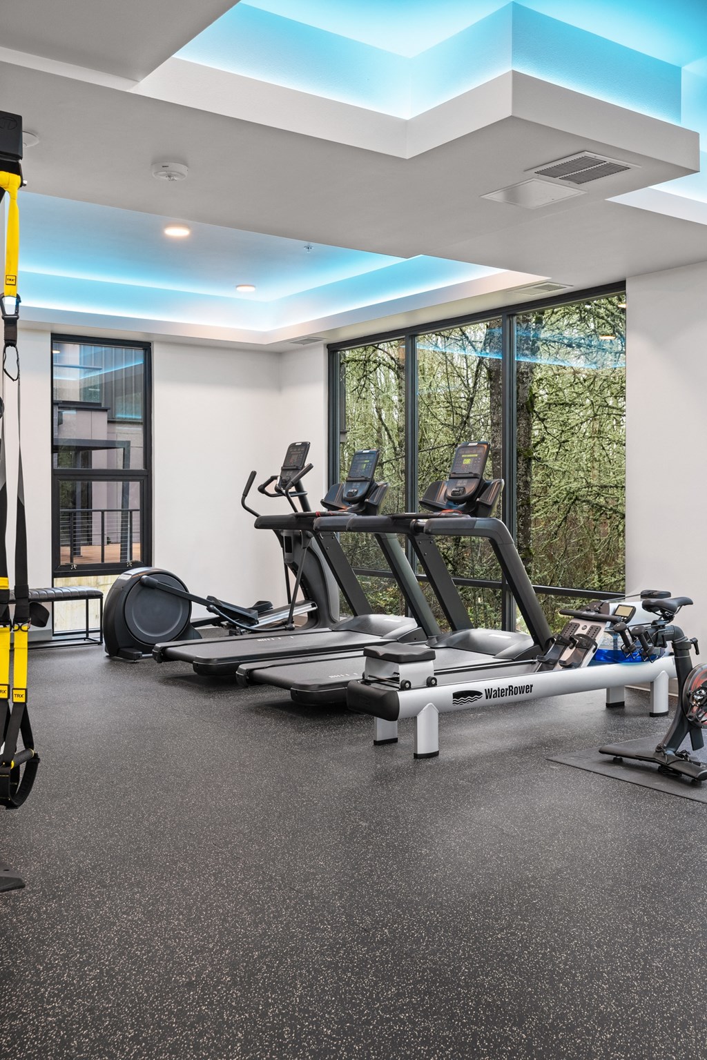 a gym with treadmills and other exercise equipment in a building with windows
